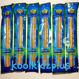 Op de afbeelding: Zes verpakkingen van Miswak natuurlijke tandenborstels worden getoond. Elke verpakking is blauw en groen, met de Miswak-stick zichtbaar. De tekst "MISWAK NATURAL TOOTHBRUSH" staat op elke verpakking.