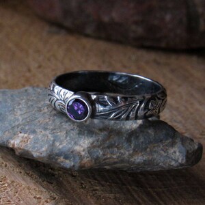 May include: A silver ring with an intricate floral design and a purple gemstone.
