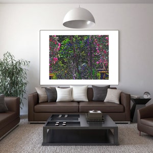 May include: A brown leather sofa with pillows in front of a framed print of a colorful floral garden scene. The sofa is in a living room setting with a coffee table and a brown leather armchair.