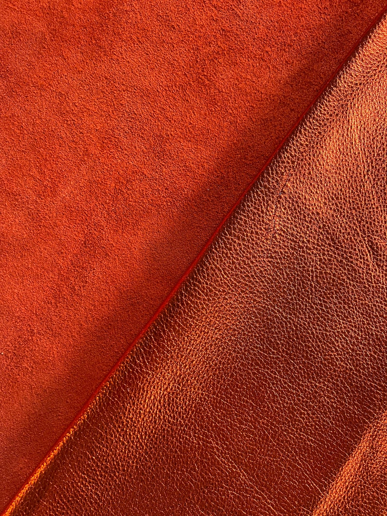 May include: Two pieces of leather fabric, one with a smooth texture and the other with a textured surface. Both are a rich, burnt orange color.