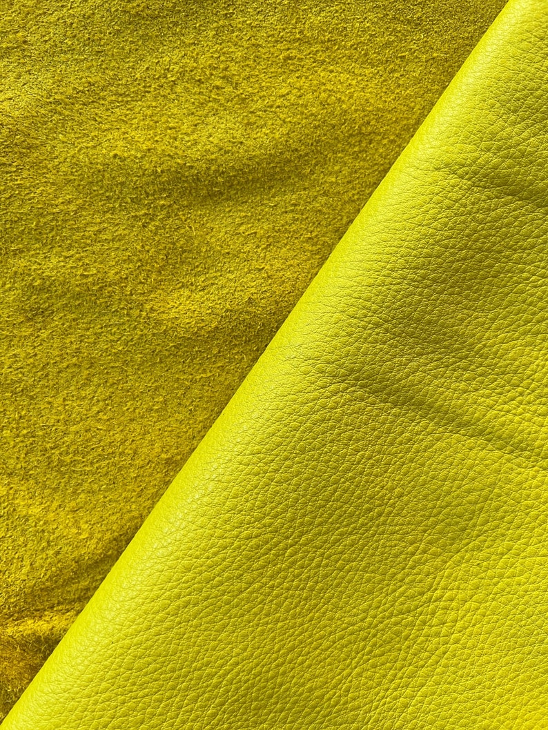 May include: Two pieces of yellow leather, one smooth and one suede, are folded over each other. The smooth leather has a textured surface.