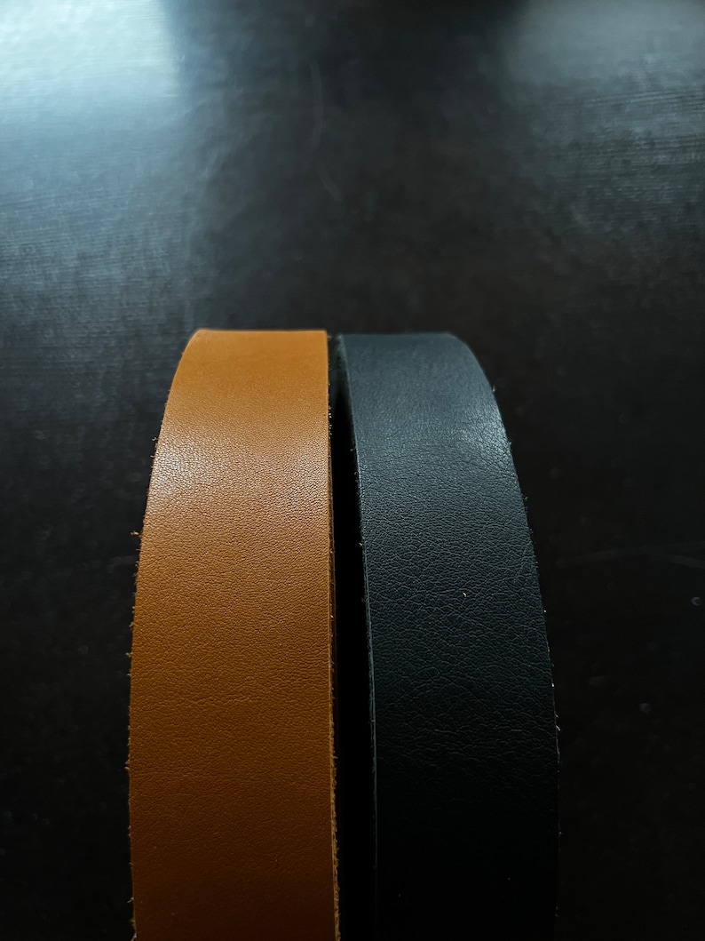 May include: Two leather straps, one brown and one black, are shown side by side. The straps are both smooth and have a slight sheen.