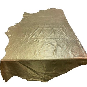 May include: A large piece of gold metallic leather with a wrinkled texture. The leather is folded in half and has a slightly irregular shape.