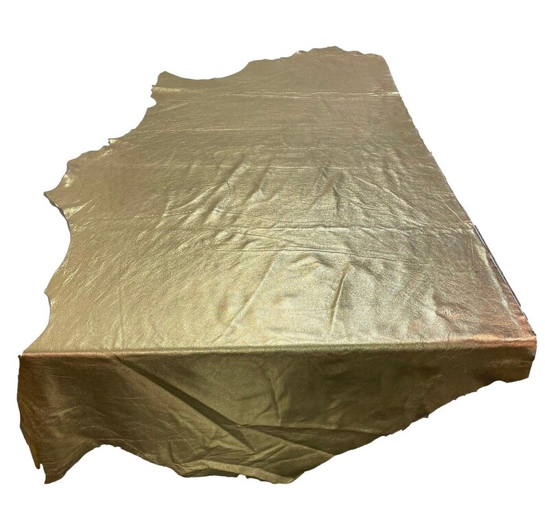 May include: A large piece of gold metallic leather with a wrinkled texture. The leather is folded in half and has a slightly irregular shape.