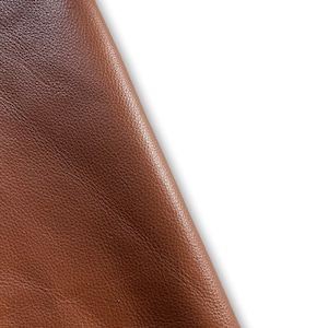 May include: Close-up of a brown leather material with a textured surface.