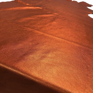 May include: A piece of metallic orange leather with a textured surface.