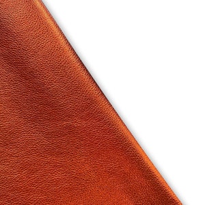 May include: Close-up of a piece of orange-brown leather with a textured surface.