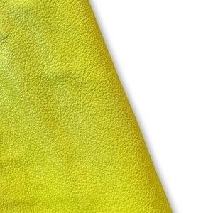May include: A close-up of a bright yellow leather material with a textured surface.