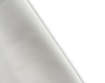 May include: A close-up of a white, textured, leather-like material. The material is folded over on itself, creating a soft, rounded edge.