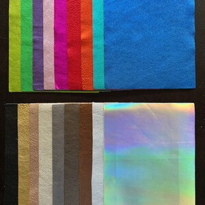 K&ouml;nnte beinhalten: Sortiment von 18 Lederproben in verschiedenen Farben und Texturen, darunter Gr&uuml;n, Lila, Pink, Rot, Orange, Blau, Schwarz, Gold, Braun, Grau und Wei&szlig;. Die Proben sind in zwei Reihen auf einer dunklen Oberfl&auml;che angeordnet.