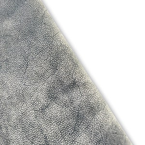 Puede incluir: Primer plano de un material de cuero gris texturizado. El cuero tiene una superficie granulada y con textura de guijarros.