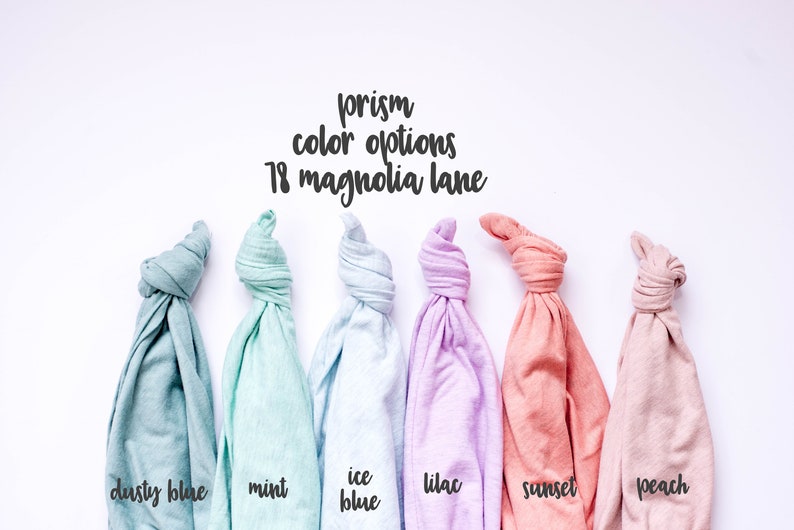 May include: Six folded t-shirts in different pastel colours: dusty blue, mint, ice blue, lilac, sunset, and peach. The text "prism colour options 18 magnolia lane" is above the shirts.