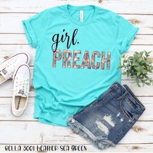 May include: A turquoise t-shirt with the text "girl. preach" in black with a floral pattern behind the text.