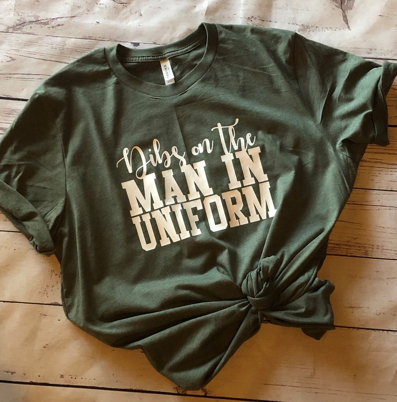 May include: A green t-shirt with the text "Dibs on the man in uniform" printed in white.