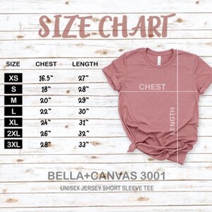 May include: Size chart for a unisex jersey short sleeve tee, showing chest and length measurements in inches for sizes XS to 3XL. The chart is printed on a light wood background.  The image also shows a pink t-shirt laid flat.