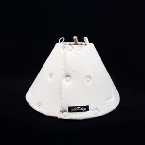 May include: White cone-shaped dog recovery collar with a white button closure and a black label that reads "million dogs".