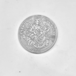 May include: A silver coin with the text "PATRONA BAVARIAE" and the year "1760". The coin features a detailed engraving of a crowned figure holding a scepter, with a child and rays of light.
