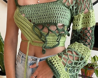 May include: A green crochet top with a unique asymmetrical design and long sleeves. The top features a loose fit and a tie at the waist.