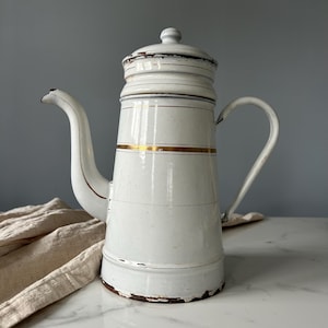 Encantadora jarra de café francesa vintage de esmalte blanco dorado con aspecto envejecido. Solo para decoración. Vajilla de esmalte desgastada y desconchada.