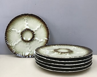May include: Set of six white oyster plates with brown scalloped edges. The plates have six individual indentations for serving oysters.