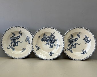 May include: Three white ceramic plates with blue floral designs. The plates have a scalloped edge and are arranged in a row.