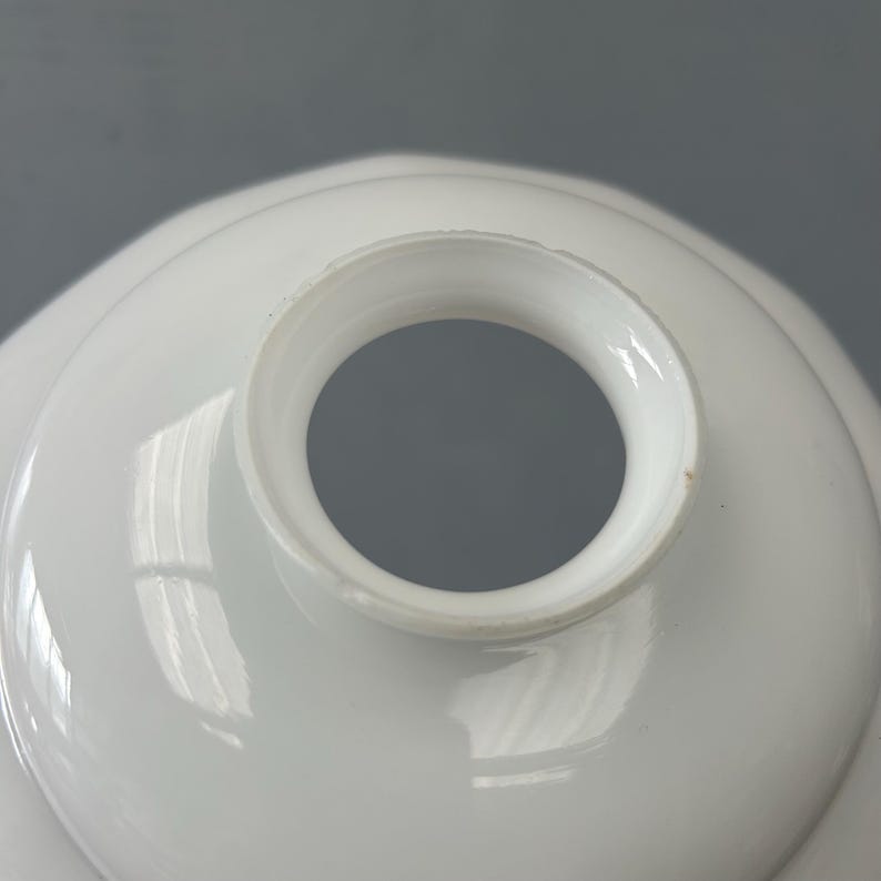 May include: A white glass lamp shade with a smooth, glossy finish and a circular opening at the top. The shade features a rounded, dome-like shape with a slightly flared collar around the central aperture, designed for attachment to a light fixture.