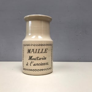 Puede incluir: Un tarro de cerámica blanco con una etiqueta negra que dice "MAILLE Mostaza à l'ancienne".