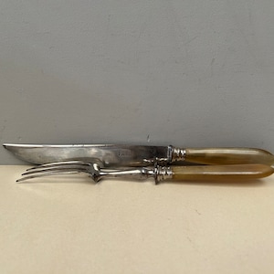 Peut inclure: Un ensemble de couteau et fourchette en argent avec des manches en os. Le couteau porte l'inscription "Paris" gravée sur la lame.