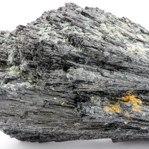 May include: A large, dark grey, rough-textured Schorl Tourmaline specimen with a few small, bright orange inclusions. The mineral has a striated, fibrous appearance.