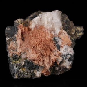 May include: A cluster of pink and white crystals on a dark gray rock. The crystals are arranged in a random pattern and have a rough texture.