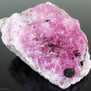 May include: A large pink and white mineral specimen with black inclusions. The mineral has a rough, textured surface.