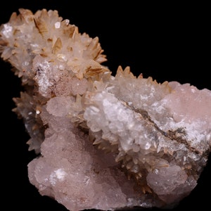 May include: A cluster of pink and brown crystals with a rough, textured surface. The crystals are arranged in a variety of shapes and sizes, creating a unique and interesting display.