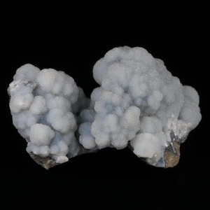 May include: A cluster of light blue mineral formations with a bubbly, textured surface. The mineral has a crystalline appearance and sits against a black background. The overall shape is irregular and organic.