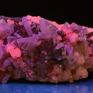 May include: A cluster of pink and purple crystals with a rough, natural texture. The crystals are arranged in a random pattern, creating a visually interesting display.