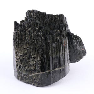 May include: A raw black tourmaline crystal specimen featuring a cluster of vertically striated, needle-like columns. The mineral has a deep, glossy black coloration with a jagged, uneven top surface and a solid, crystalline structure throughout.