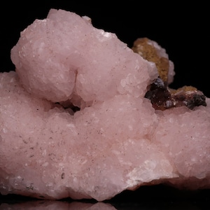 May include: A cluster of pink and brown mineral specimens. The pink mineral has a rough, textured surface. The brown mineral is smooth and has a darker color.