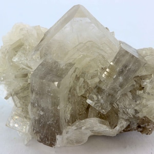 May include: A cluster of clear, translucent, and slightly brown crystals with a sharp, geometric shape.