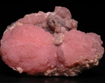 Può includere: Un gruppo di campioni minerali rosa e bianchi con una superficie ruvida e testurizzata. Il minerale rosa è il colore dominante e ha una forma liscia e arrotondata.