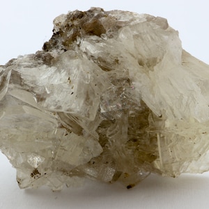 May include: A cluster of clear, translucent crystals with a rough, brown, earthy matrix. The crystals are clustered together in a random, organic shape.