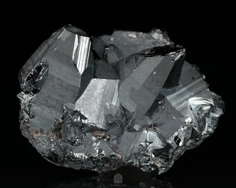 May include: A cluster of dark gray, metallic hematite crystals with a reflective, almost iridescent sheen. The crystals are sharp and angular, with a rough, textured surface.