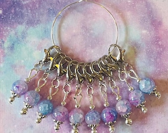 Puede incluir: Un juego de 10 marcadores de punto con anillos de metal plateado y cuentas de ágata púrpura y azul. Los marcadores están unidos a un anillo de metal plateado.