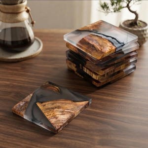 May include: A stack of five square coasters and one individual coaster, each crafted from natural wood grain and translucent black resin. The coasters feature a smooth, polished finish with visible wood textures and dark, smoky resin accents.