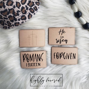 以下が含まれることがあります： 黒い文字が書かれたベージュの革のパッチが4つ。パッチには、「He is risen」、「FORGIVEN」、「ROMANS 1-SIXTEEN」、そして3つの十字架が書かれている。