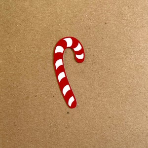 May include: A red and white candy cane cutout. The candy cane is a traditional Christmas decoration.