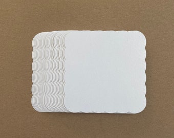 May include: A stack of white scalloped edge cardstock paper.