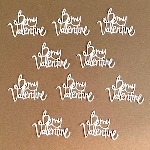 May include: Nine white paper cutouts of the phrase "Bemy Valentine" in a cursive font.