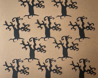 May include: Ten black paper cutouts of spooky trees with twisting branches. The trees are arranged in a symmetrical pattern on a brown background.