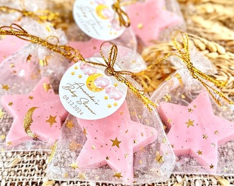May include: Pink star-shaped favors in clear organza bags with gold ribbon ties. Each bag has a round tag with a moon and clouds design and the text "Amanda's Baby Shower 09.12.2024".