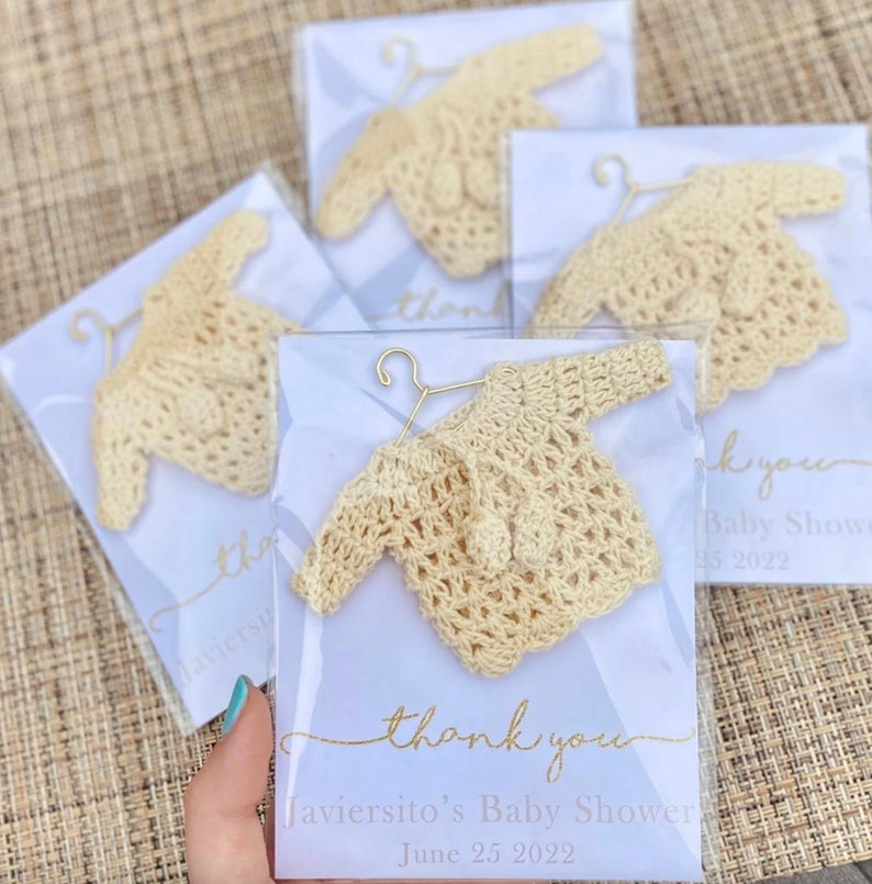 May include: Thank you card with a crocheted baby sweater on a hanger. The card says "Thank you" and "Javiersito's Baby Shower June 25 2022".