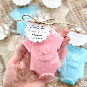 Puede incluir: Jabones en forma de mono de beb&eacute; rosa y azul con purpurina dorada y una etiqueta de agradecimiento que dice "Gracias por celebrar el nacimiento de Baby Jones con amor - Amy & John".